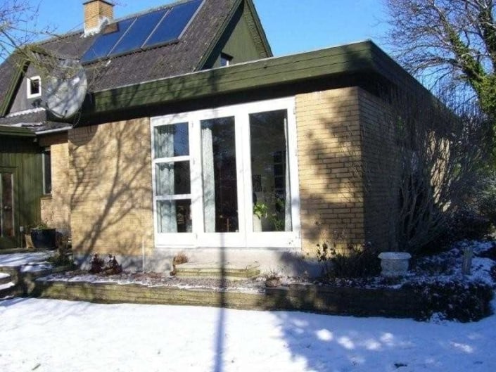 Murstenshus med solceller på taget om vinteren