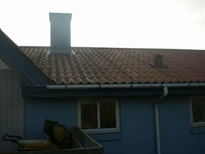 Blåt hus med tegltag og skorsten