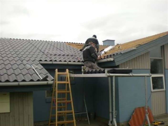 To håndværkere arbejder på isolering af tag